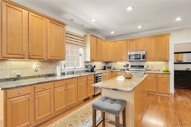 kitchen with light wood-style flooring, a sink, light stone counters, a center island, and appliances with stainless steel finishes