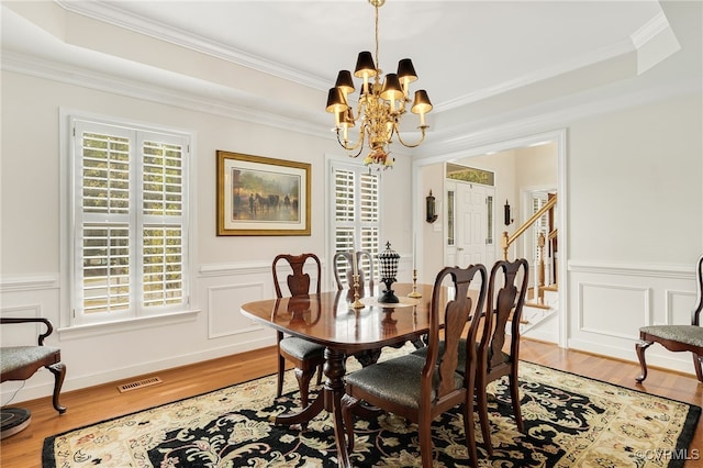 dining space with light wood-type flooring, visible vents, an inviting chandelier, and a tray ceiling