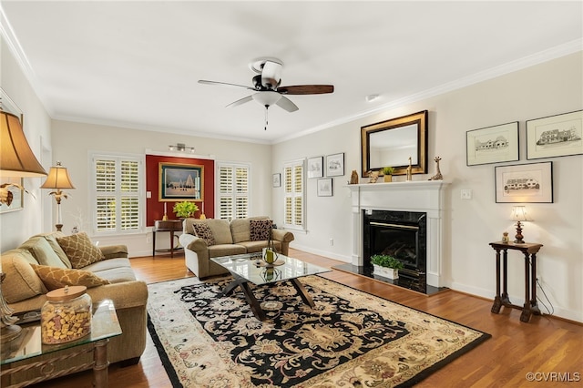 living area featuring ornamental molding, a fireplace, baseboards, and wood finished floors