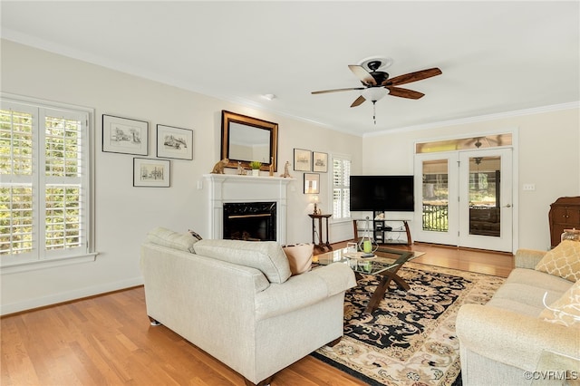 living room with light wood finished floors, a fireplace, crown molding, and ceiling fan