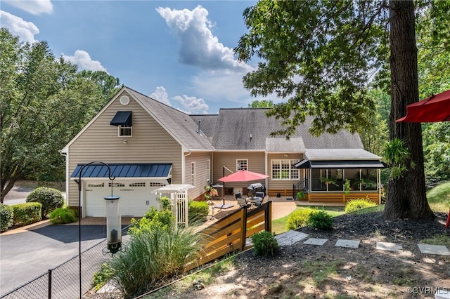 view of front of property with fence, roof with shingles, a garage, a sunroom, and driveway