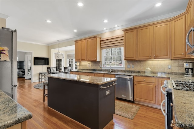 kitchen featuring a kitchen island, light wood-style flooring, stainless steel appliances, and crown molding