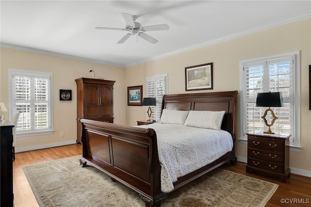 bedroom with a ceiling fan, crown molding, baseboards, and wood finished floors