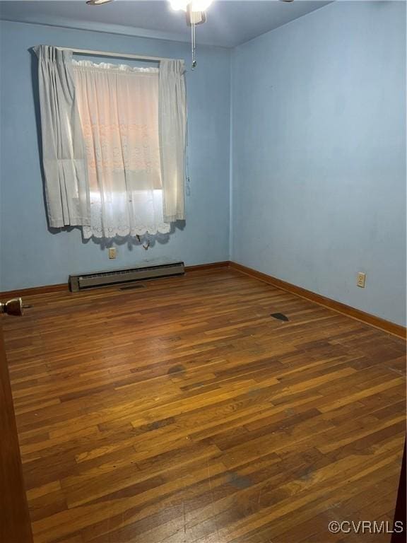 unfurnished room featuring a baseboard heating unit, baseboards, and dark wood-type flooring