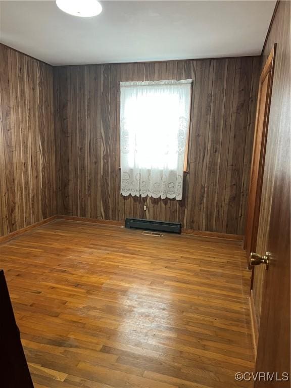 spare room featuring wooden walls, visible vents, and wood finished floors