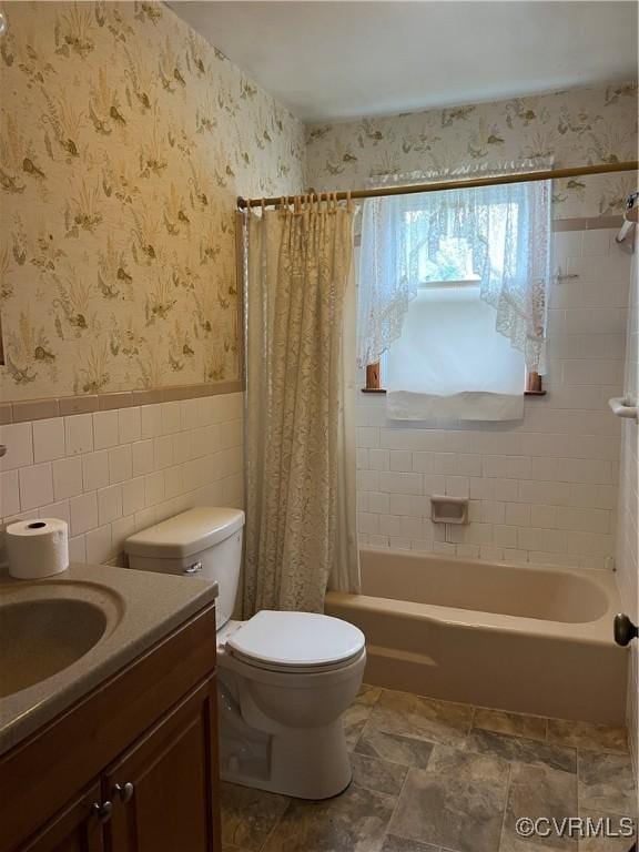 bathroom with wallpapered walls, tile walls, a wainscoted wall, toilet, and vanity