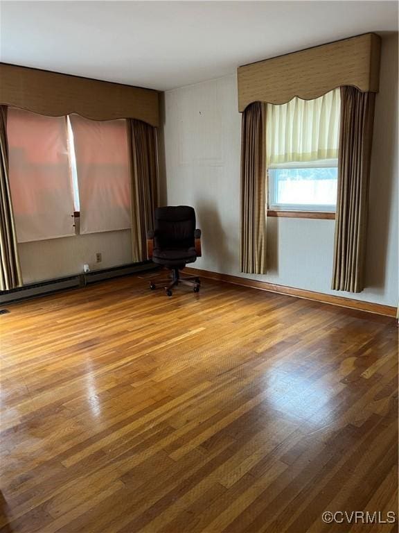 empty room with baseboard heating and wood finished floors