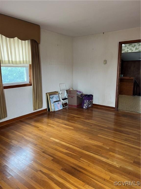 empty room with baseboards and hardwood / wood-style flooring