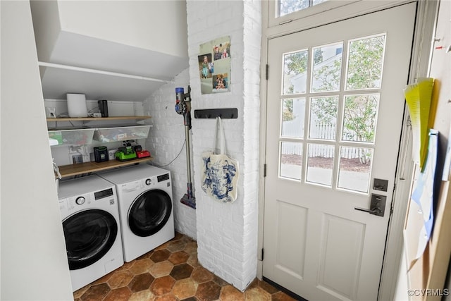 laundry area featuring plenty of natural light, separate washer and dryer, brick wall, and laundry area