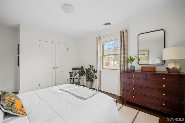 bedroom featuring wood finished floors, visible vents, and a closet