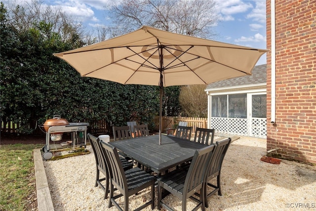 view of patio / terrace featuring outdoor dining space, a grill, a sunroom, and fence