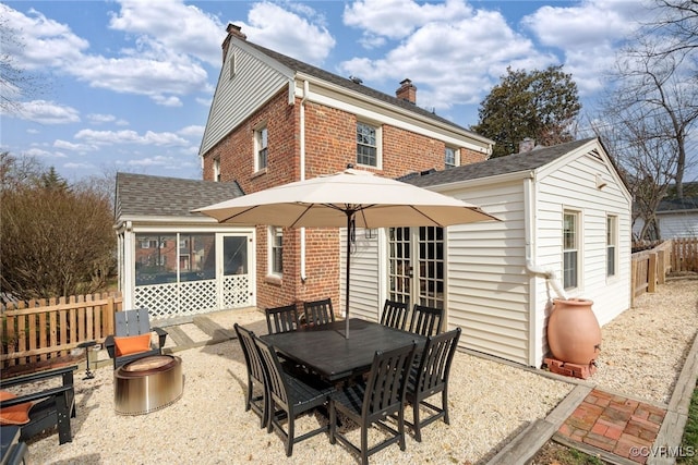 back of house featuring brick siding, fence, roof with shingles, french doors, and a chimney