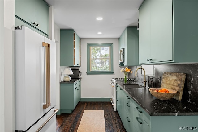 kitchen featuring white appliances, green cabinetry, dark wood-style flooring, a sink, and tasteful backsplash