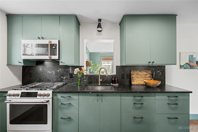 kitchen featuring backsplash, gas stove, green cabinets, and a sink