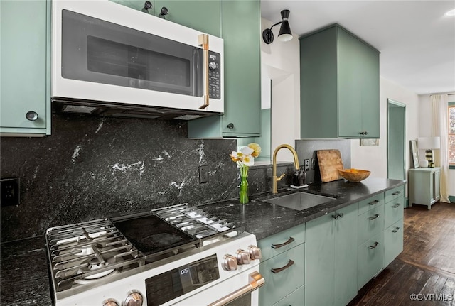 kitchen featuring dark wood-style floors, white microwave, a sink, green cabinets, and stainless steel gas stove