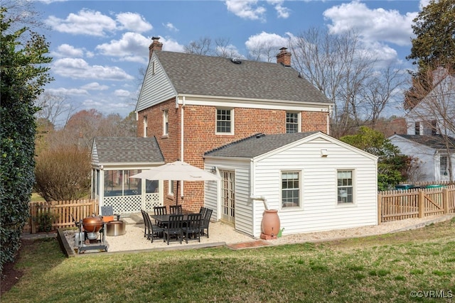 rear view of house featuring brick siding, fence, roof with shingles, a lawn, and a patio