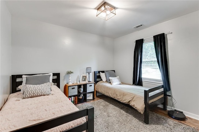 bedroom with wood finished floors, visible vents, and baseboards