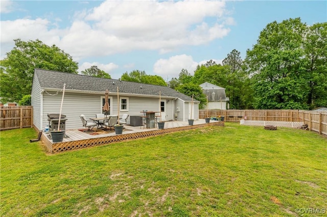 rear view of house featuring a deck, a yard, and a fenced backyard