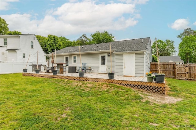 rear view of property with a deck, a lawn, central AC, and a fenced backyard