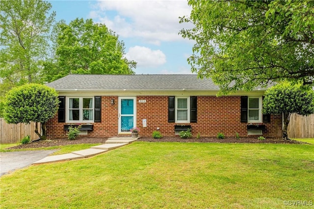 ranch-style home featuring brick siding, a front lawn, and fence