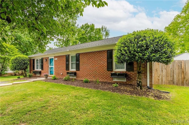 ranch-style home with brick siding, a front lawn, and fence