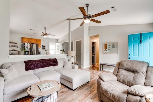 living area featuring a ceiling fan, visible vents, baseboards, lofted ceiling, and light wood-style floors