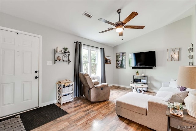 living room featuring light wood finished floors, visible vents, baseboards, lofted ceiling, and a ceiling fan