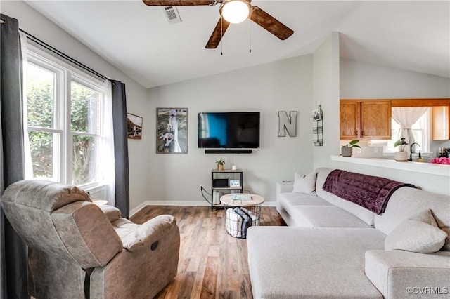 living area with visible vents, ceiling fan, baseboards, vaulted ceiling, and wood finished floors