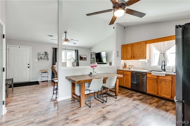 kitchen with light wood-type flooring, brown cabinets, dishwasher, and freestanding refrigerator