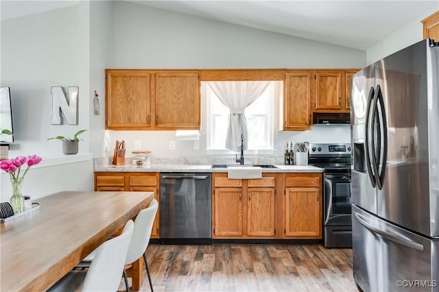 kitchen featuring dark wood-type flooring, light countertops, vaulted ceiling, appliances with stainless steel finishes, and a sink