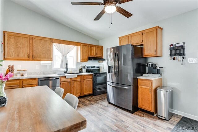 kitchen with lofted ceiling, a sink, light countertops, under cabinet range hood, and appliances with stainless steel finishes