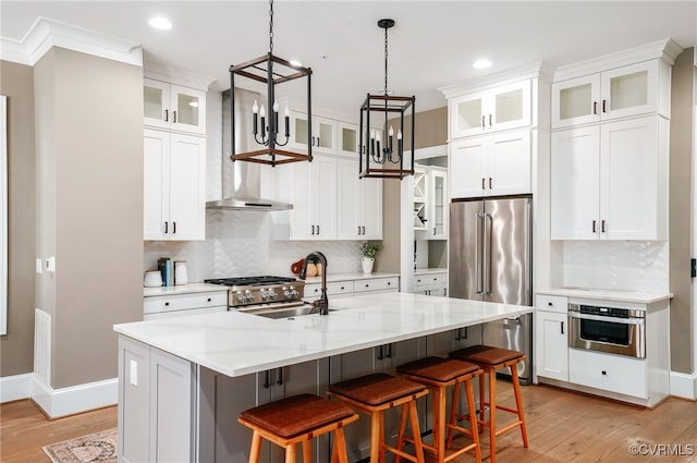 kitchen with light wood finished floors, a center island with sink, white cabinets, and stainless steel appliances