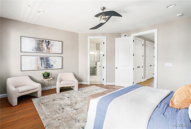 bedroom featuring a ceiling fan, baseboards, visible vents, ensuite bath, and light wood-style flooring