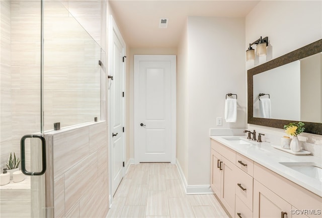 full bath featuring a sink, baseboards, double vanity, and a shower stall