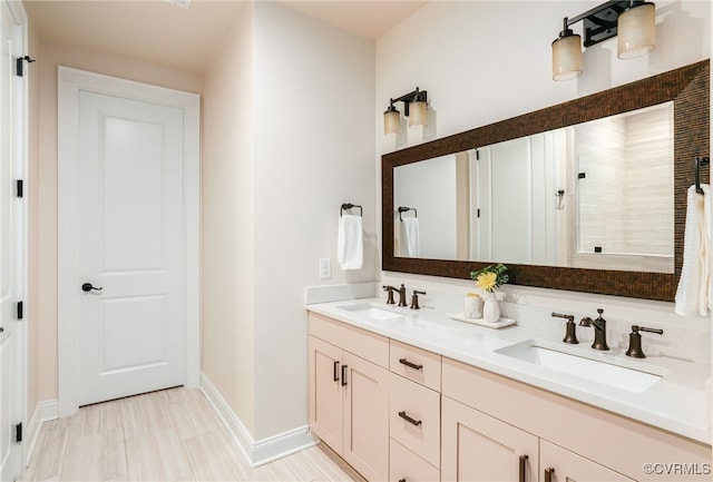 full bath with double vanity, tiled shower, baseboards, and a sink