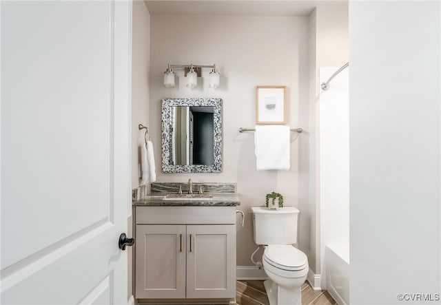 bathroom with toilet, wood finished floors, baseboards, bathing tub / shower combination, and vanity