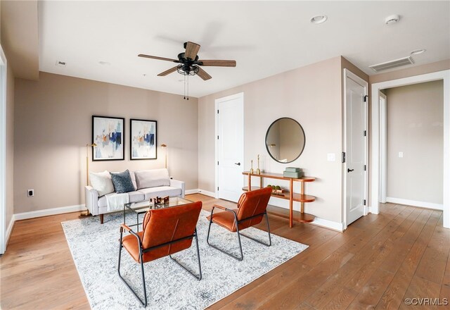 living room featuring visible vents, light wood-type flooring, and baseboards