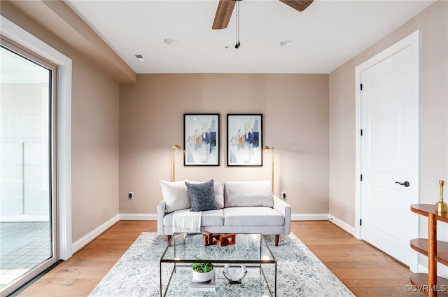 living room with light wood-style flooring, visible vents, baseboards, and ceiling fan