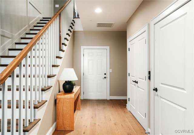 foyer featuring visible vents, light wood-style flooring, recessed lighting, baseboards, and stairs