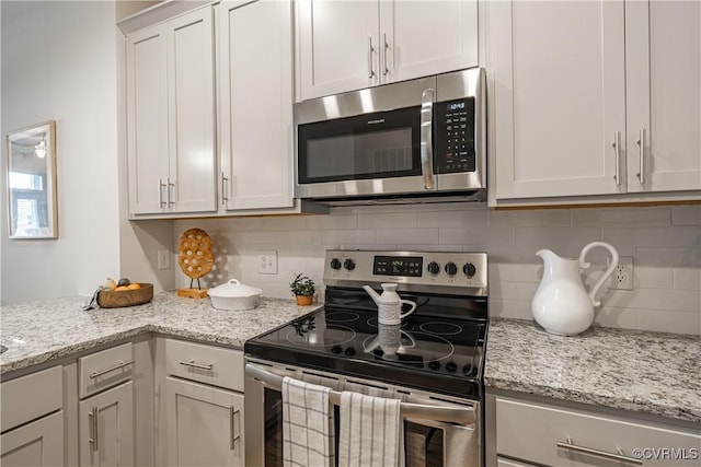 kitchen featuring stainless steel appliances, light stone countertops, and tasteful backsplash