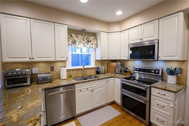 kitchen featuring a sink, backsplash, appliances with stainless steel finishes, and white cabinets