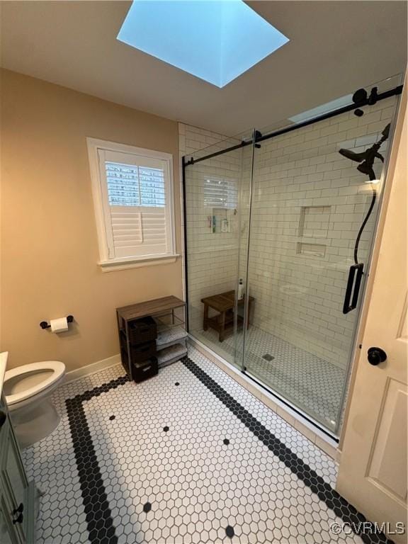 full bathroom featuring baseboards, toilet, a stall shower, a skylight, and tile patterned floors