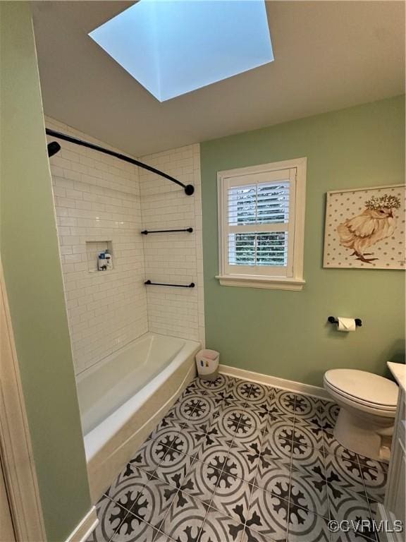 bathroom with tile patterned flooring, baseboards, toilet, a skylight, and vanity