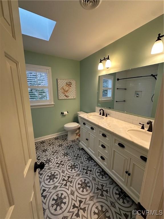 bathroom with a sink, toilet, a skylight, and tile patterned flooring