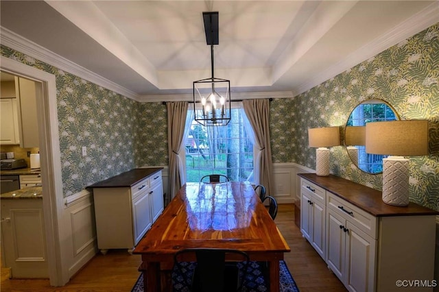 dining area featuring a wainscoted wall, a raised ceiling, dark wood-type flooring, and wallpapered walls