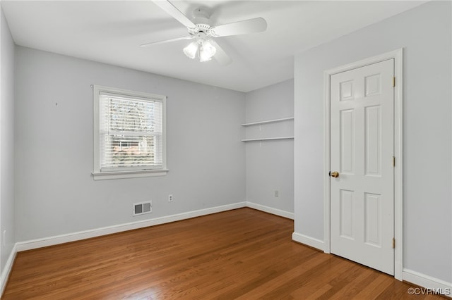 unfurnished bedroom with visible vents, baseboards, wood finished floors, and a ceiling fan