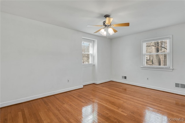 spare room with a ceiling fan, light wood-style floors, visible vents, and baseboards