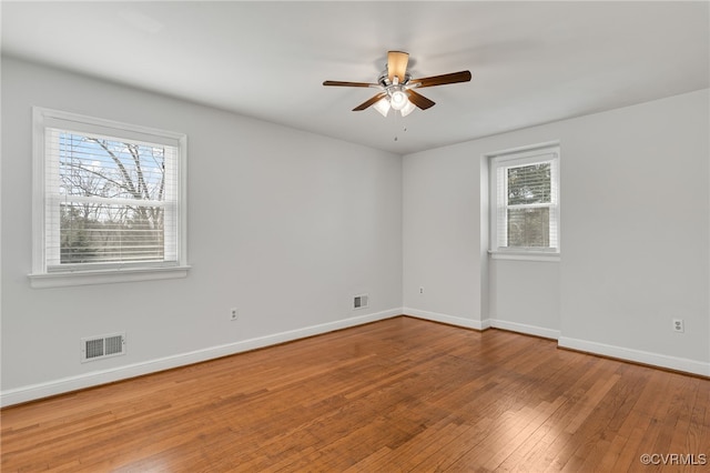 empty room with visible vents, wood-type flooring, baseboards, and ceiling fan