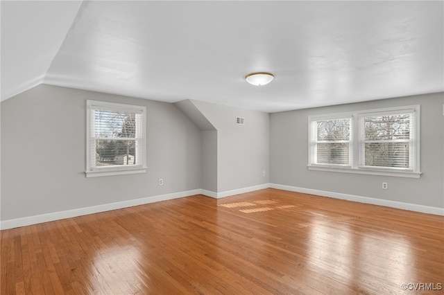 bonus room featuring visible vents, baseboards, light wood-style floors, and lofted ceiling