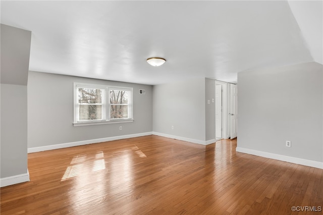 unfurnished living room featuring visible vents, baseboards, and wood-type flooring